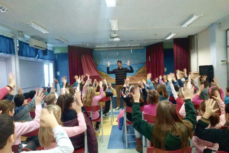 Κατάμεστο σχολικό θέατρο με μαθητές και μαθήτριες να χειροκροτούν μαζί με τον Κωνσταντίνο στην νοηματική.
